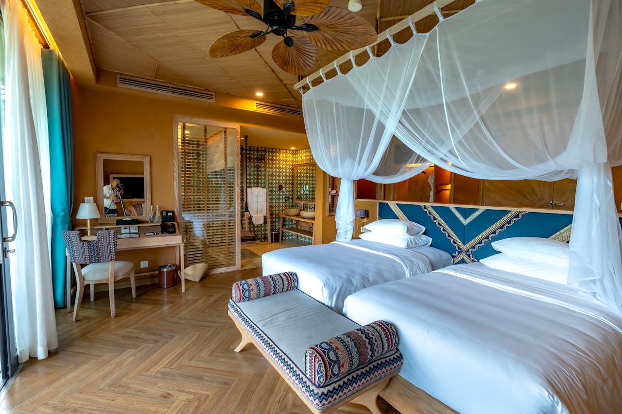 Elegant resort room with canopy bed, wooden decor, and modern amenities.